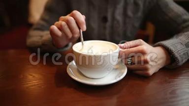一个沮丧的年轻不耐烦的女孩在一个白色的杯子里搅动糖。 疲惫的女人在等男朋友，她很无聊。